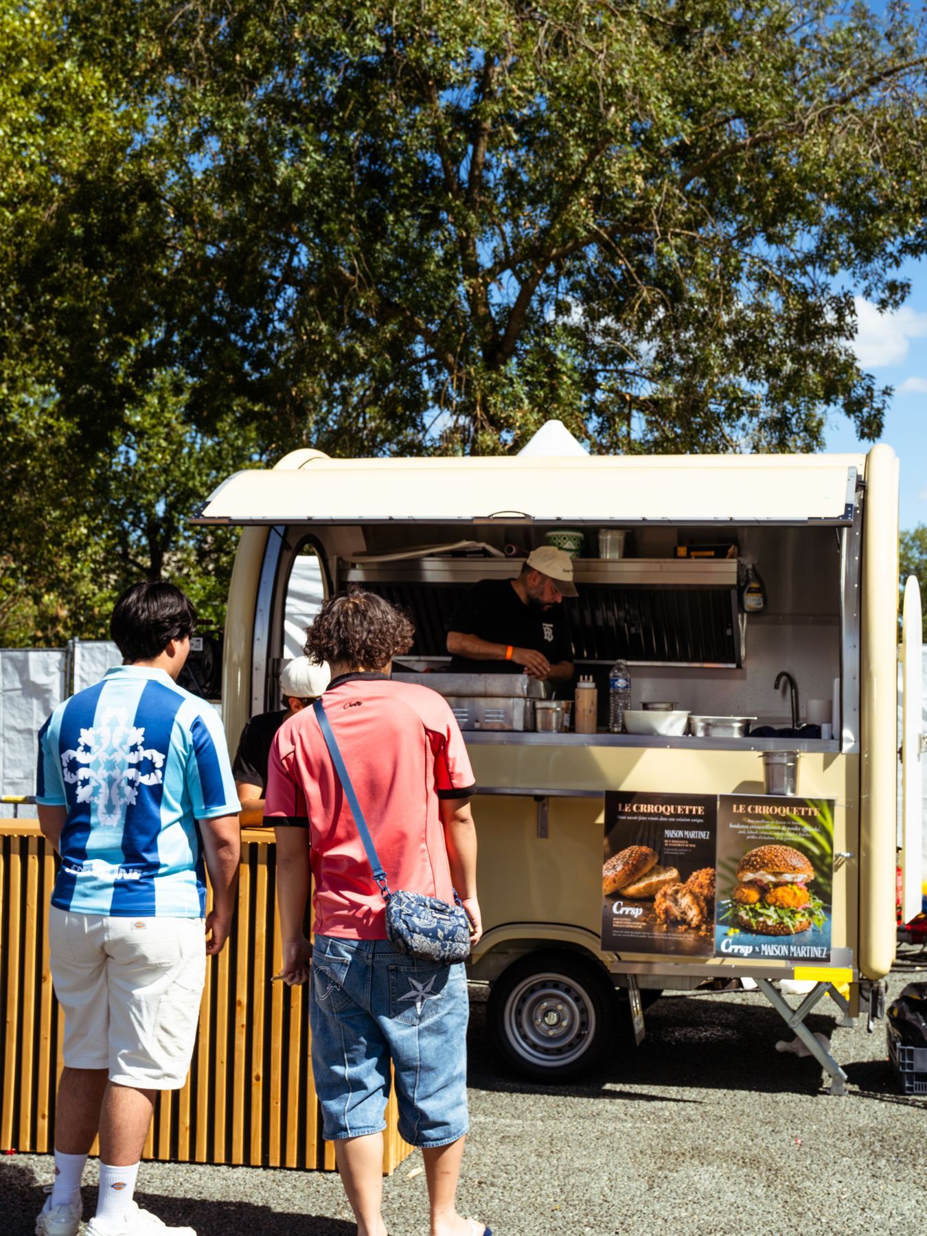 Rimorchio street food beige in pieno servizio, con i clienti al bancone