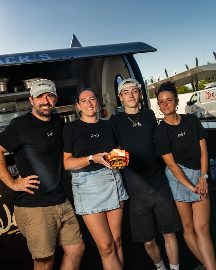 Il team di Jack’s Burger davanti al proprio rimorchio food truck, con un hamburger in mano